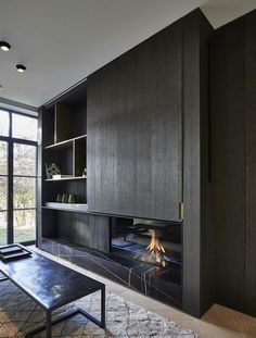 a living room with a fire place next to a large window and a bench in front of the fireplace