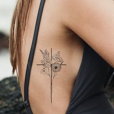 a woman with a cross and flowers tattoo on her upper back side ribcage