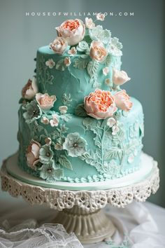 a three tiered blue cake with flowers on it