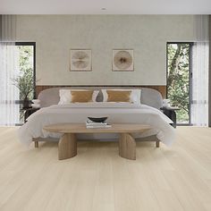 a large white bed sitting in a bedroom next to a wooden table and window sill