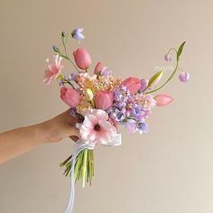 a person holding a bouquet of flowers in their hand with the stems still attached to it