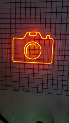 a neon camera sitting on top of a wall