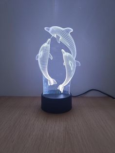 a lamp that has two dolphins in it on a wooden table next to a wall