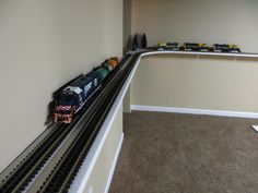 there is a toy train set in the corner of this room with no people on it