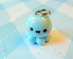 a small blue toy sitting on top of a checkered tablecloth with a metal keychain