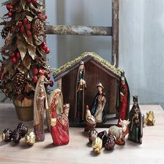 a nativity scene with figurines in front of a christmas tree and other decorations