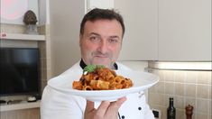 a man is holding a plate with food on it in his hands and looking at the camera