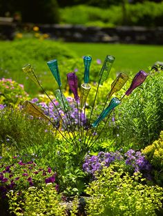 there are many different colored glass bottles in the flowerbeds and bushes, one is purple