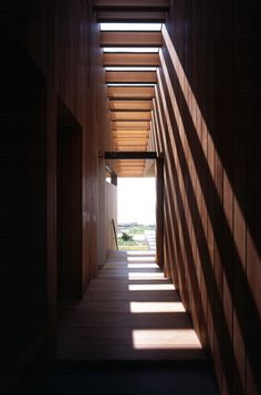 the hallway is lined with wooden slats and has sunlight streaming in through the windows