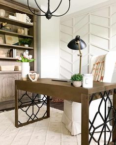 a desk with a laptop and flowers on it in front of a bookshelf