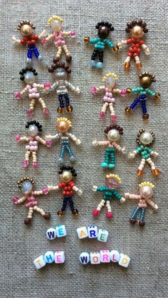 several small beaded dolls are arranged in the shape of words that spell out we are the world