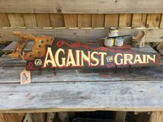 a sign that says against the grain on a wooden bench with other items around it