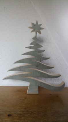 a metal christmas tree on top of a wooden table in front of a white wall