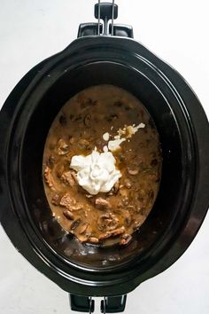 a crock pot filled with stew and sour cream