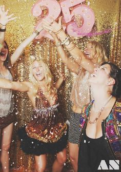 three women in sequins are holding up the number 50 sign and confetti