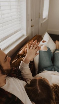 a man and woman laying on a bed with their hands in the air