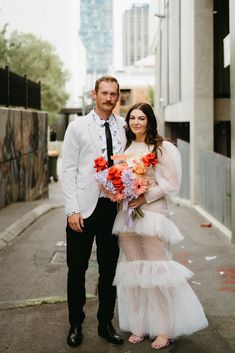 a man and woman standing next to each other in front of a city street with tall buildings