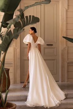 a woman in a white dress is standing on the stairs and looking off into the distance