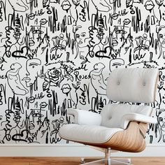 an eames chair in front of a wall with black and white graffiti on it