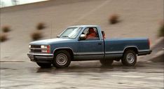 a blue pick up truck driving down a road