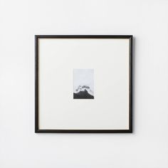 a black and white photo hanging on the wall next to a framed art print with mountains in the background