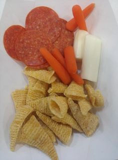 some food is laying out on a white plate with crackers, cheese and carrots