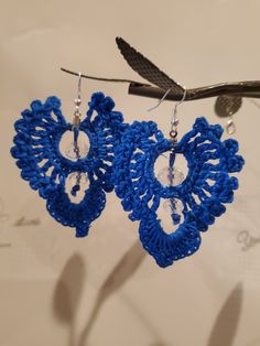 a pair of blue crocheted earrings hanging from a hook on a wire with scissors