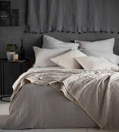 a bed that has some pillows on top of it in a room with grey walls