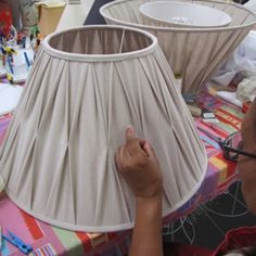 a woman is working on a lamp shade