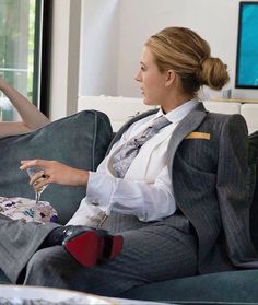 a woman sitting on top of a couch next to a man in a suit and tie