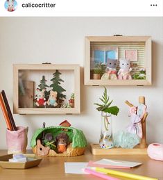 there are three wooden boxes with stuffed animals in them on the table next to other items