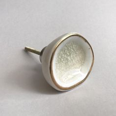 a close up of a white and gold knob on a white surface with no background