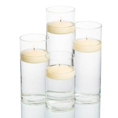 four clear glass vases with candles in them