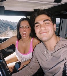 a man and woman sitting in the driver's seat of a vehicle with their mouths open