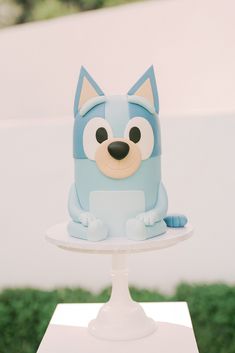 there is a cake that looks like a cat on top of a stand with grass in the background