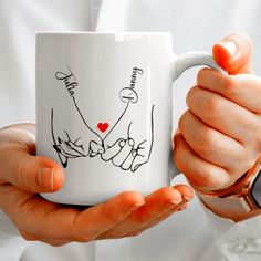 a person holding a coffee mug with writing on it and two hands in front of them