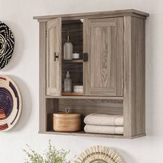 a wooden cabinet sitting on top of a wall next to a basket and vase filled with flowers