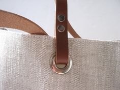 Modern simplicity and casual styling in a neutral oatmeal color will keep this bag classic year after year. Details: -Size: Approximately 14in H x 5in ) x 17in W at top, 12in W at bottom [Approximately 35.5cm (H) x 12.7cm (D) x 43cm (W) at top and 30cm (W) at bottom] -Approximately 9in handle drop (23cm) -Leather handles in Brown or Weathered Tan -Magnetic snap closure -Medium weight textured linen exterior -Durable Twill lining -3 interior slip pockets and 1 large zippered pocket -Stress points Simple Linen, Linen Tote Bag, Waxed Canvas Bag, Simple Tote, Oatmeal Color, Patchwork Bags, Bag Patterns To Sew, Brown Leather Strap, Linen Bag