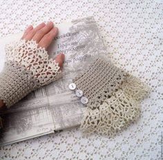 a pair of knitted gloves sitting on top of a white cloth covered tablecloth