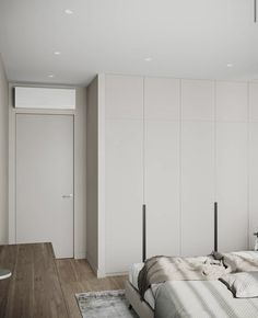 a bedroom with white walls and wooden flooring is pictured in this image, there are two beds on the opposite side of the room