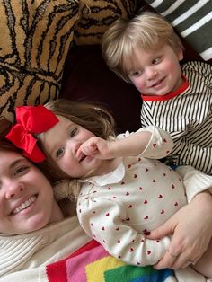 a woman and two children laying on top of a bed