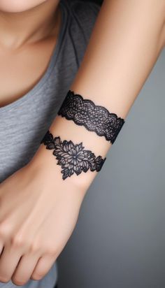 a woman's arm with a black lace wristband on her left hand and an intricate flower design on the right wrist