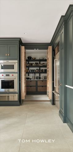 an open kitchen with green cabinets and white counter tops, along with built - in ovens