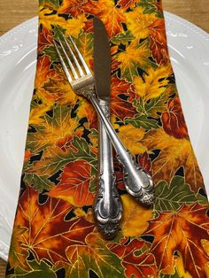 a fork and knife sitting on top of a place mat with leaves patterning it