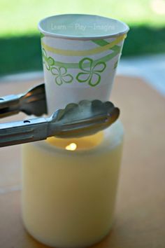 a plastic cup sitting on top of a wooden table next to a metal utensil