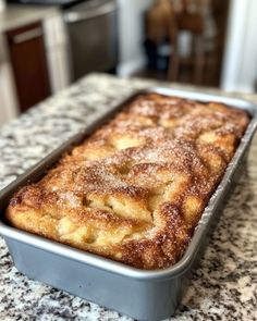 a cake in a pan sitting on top of a kitchen counter covered in powdered sugar