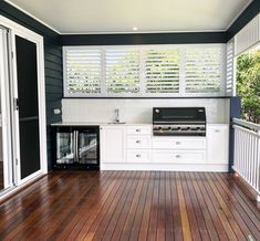 an outdoor kitchen with wood floors and white cabinets on the outside wall, along with sliding glass doors