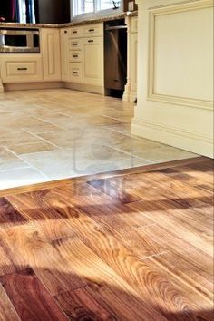 an empty kitchen with wood floors and white cabinets in the background is a large open floor plan