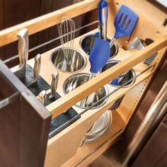 an open drawer in a kitchen with utensils and other items inside the drawers