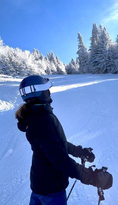 a person on skis in the snow with some trees behind them and blue sky